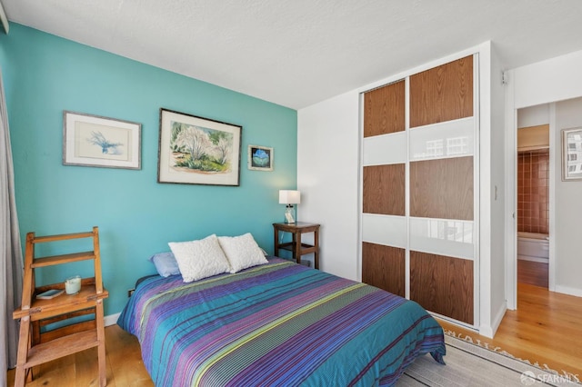bedroom featuring wood finished floors, baseboards, and a closet