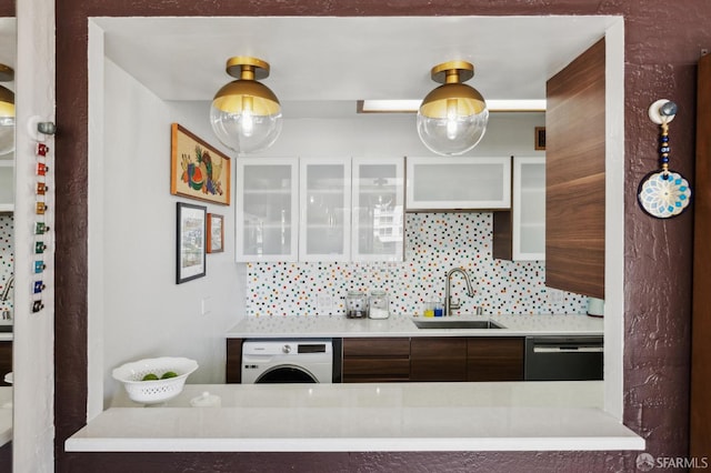 kitchen featuring washer / clothes dryer, a sink, dishwasher, and light countertops