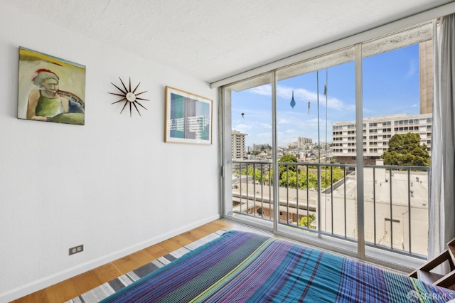 unfurnished bedroom featuring baseboards, wood finished floors, and a view of city