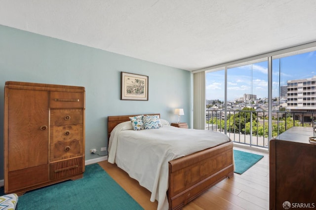 bedroom featuring a view of city, access to exterior, expansive windows, and a textured ceiling