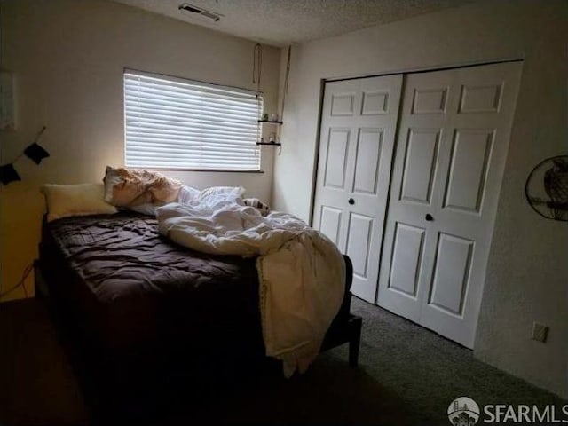 bedroom with a closet, carpet, and a textured ceiling