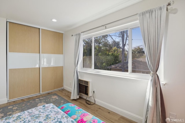 unfurnished bedroom with a closet, a wall unit AC, and light wood-type flooring