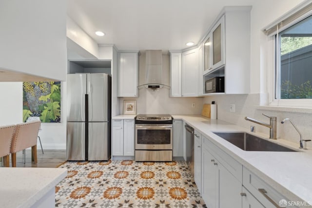 kitchen featuring tasteful backsplash, white cabinetry, sink, stainless steel appliances, and wall chimney exhaust hood