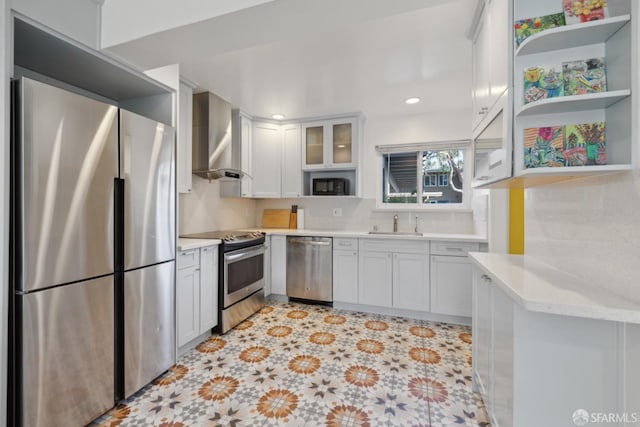 kitchen featuring stainless steel appliances, white cabinetry, sink, and wall chimney range hood