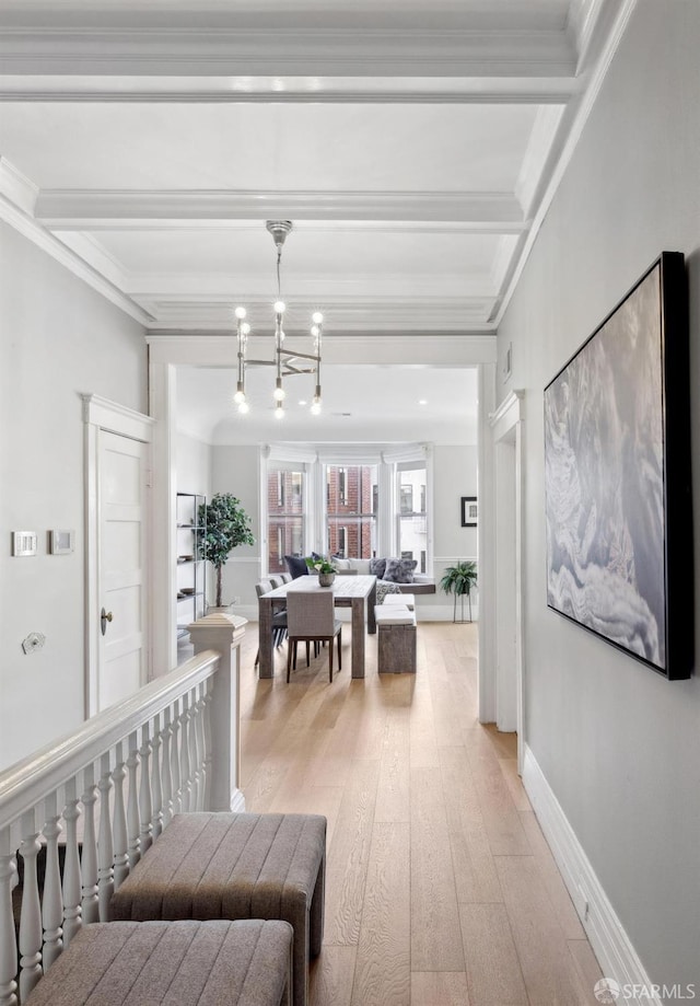 hallway with light wood-style floors, crown molding, beamed ceiling, and an inviting chandelier