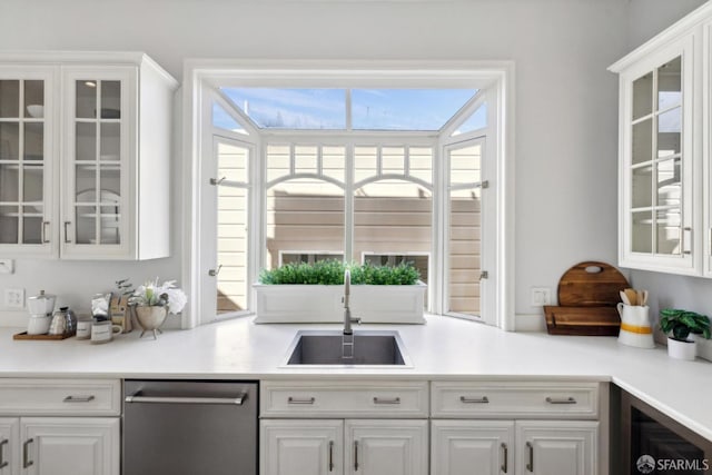 kitchen featuring a wealth of natural light, white cabinets, a sink, and dishwasher