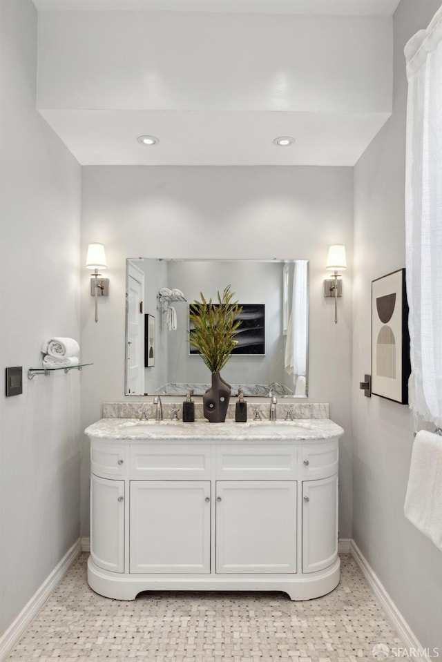 bathroom with double vanity, a sink, and baseboards