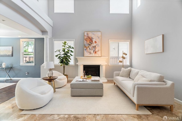 living room featuring a glass covered fireplace, a towering ceiling, and baseboards