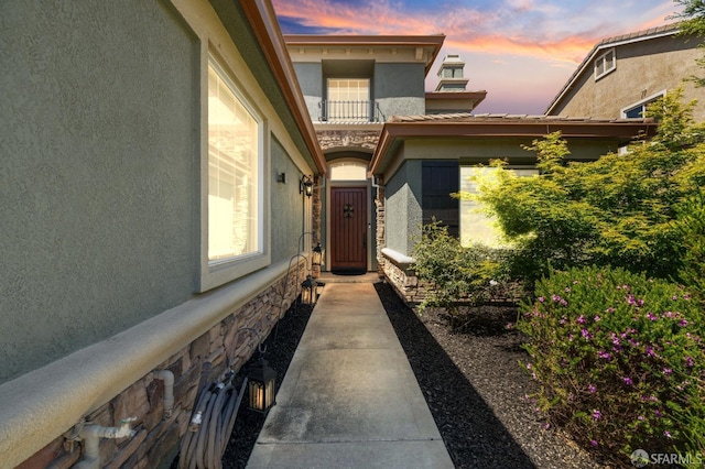 entrance to property featuring stone siding and stucco siding