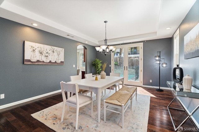 dining room with visible vents, arched walkways, a raised ceiling, and dark wood-style flooring