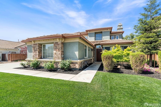 prairie-style house featuring a tile roof, stone siding, fence, a front yard, and stucco siding