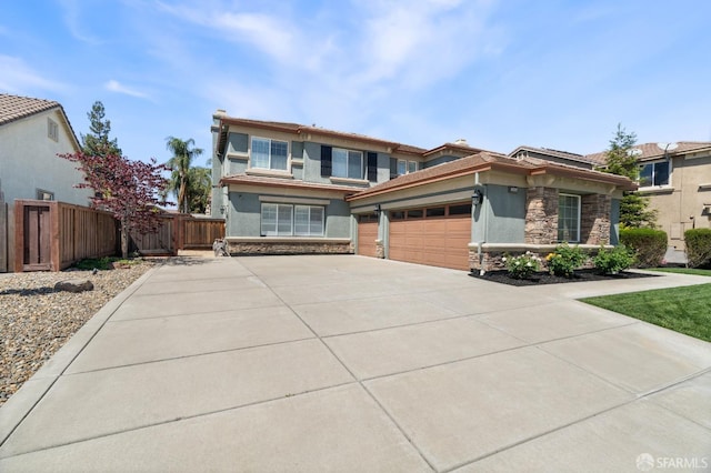 prairie-style home with driveway, stone siding, fence, an attached garage, and stucco siding