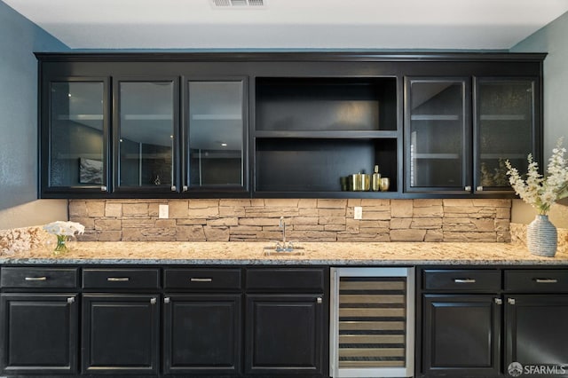 bar featuring bar area, a sink, visible vents, decorative backsplash, and beverage cooler