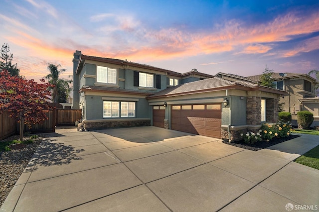 view of front of home featuring stone siding, concrete driveway, fence, a garage, and stucco siding
