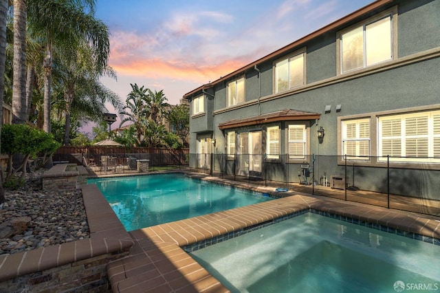 pool at dusk featuring a fenced backyard, a patio area, and a fenced in pool