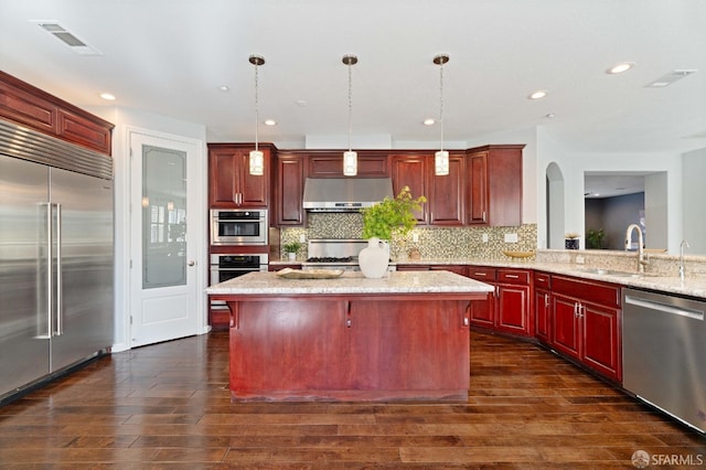 kitchen featuring a center island, a sink, stainless steel appliances, under cabinet range hood, and visible vents