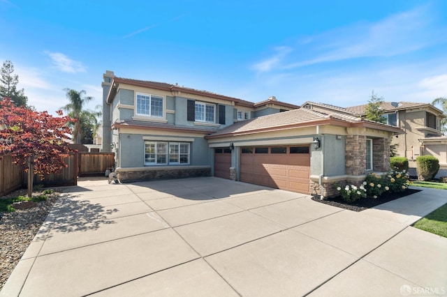 prairie-style home featuring stone siding, concrete driveway, fence, an attached garage, and stucco siding