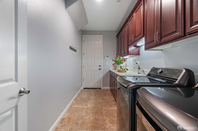 laundry room featuring a sink, washer and clothes dryer, baseboards, stone finish flooring, and cabinet space