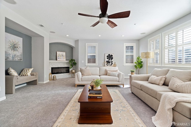 living room with a glass covered fireplace, visible vents, recessed lighting, carpet, and ceiling fan