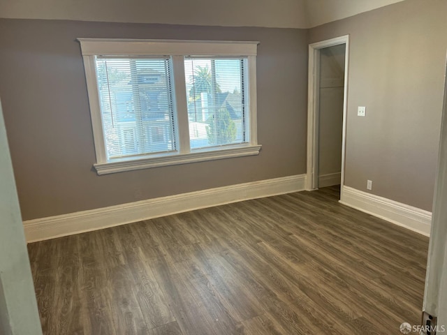 spare room with dark wood finished floors and baseboards