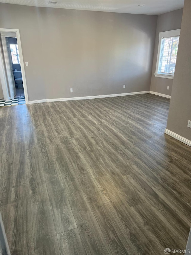 empty room featuring baseboards and dark wood-style flooring