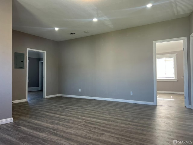 unfurnished room featuring dark wood finished floors, electric panel, recessed lighting, and baseboards