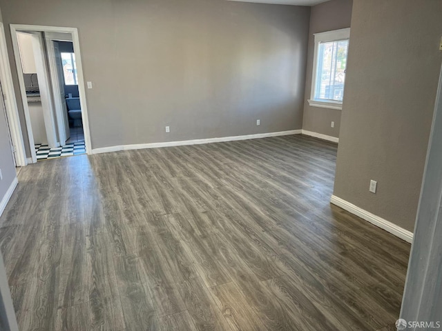 spare room featuring dark wood finished floors and baseboards