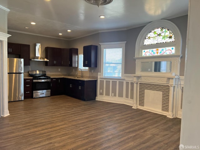 kitchen with ornamental molding, a sink, dark wood finished floors, appliances with stainless steel finishes, and wall chimney range hood