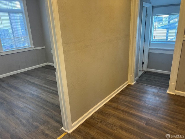 corridor featuring dark wood-style floors and baseboards