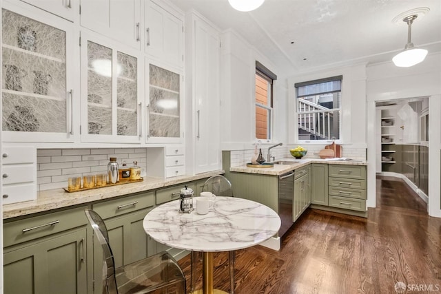 kitchen featuring pendant lighting, stainless steel dishwasher, green cabinets, and decorative backsplash