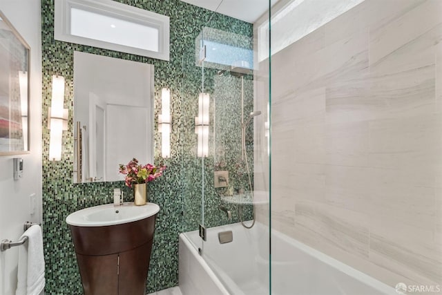 bathroom featuring tasteful backsplash, vanity, tile walls, and shower / bath combination with glass door