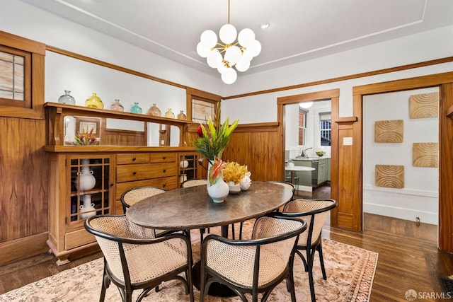 dining area with dark hardwood / wood-style flooring, a notable chandelier, and wood walls