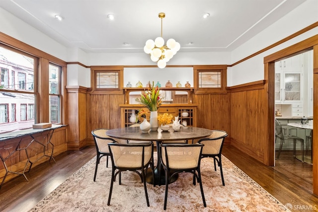 dining area featuring hardwood / wood-style flooring, wooden walls, and a chandelier