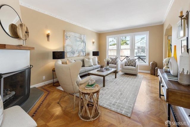 living area featuring baseboards, a fireplace with raised hearth, and ornamental molding