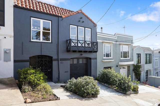 view of front facade featuring an attached garage, a tiled roof, concrete driveway, and stucco siding