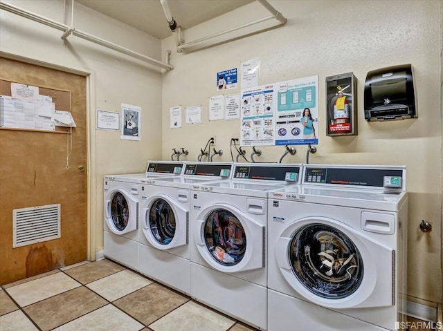 clothes washing area with washing machine and clothes dryer and light tile patterned floors