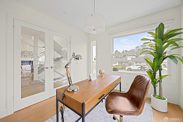 home office with light wood-style floors and french doors