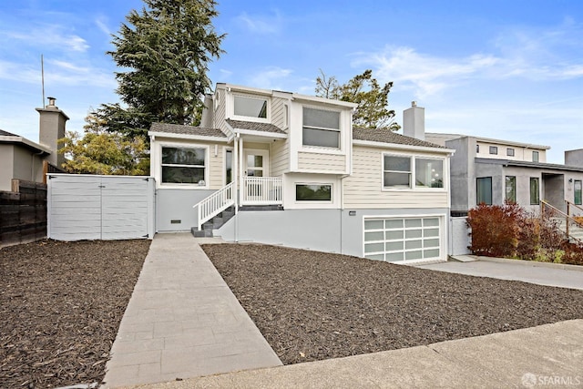 view of front of property featuring a garage, a chimney, fence, and concrete driveway