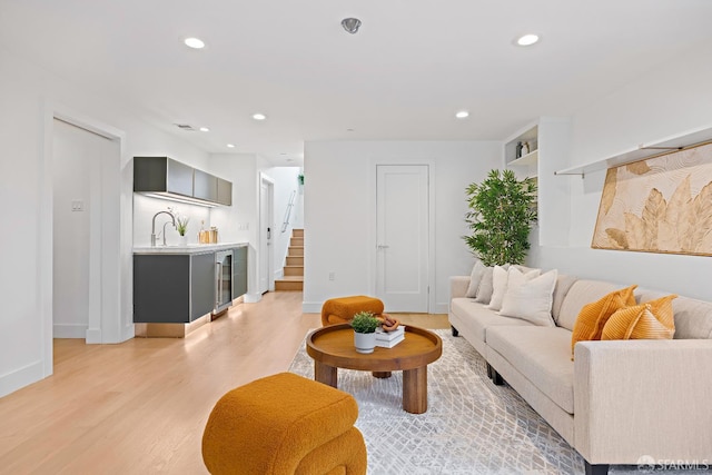 living room with beverage cooler, stairway, light wood-style flooring, and recessed lighting