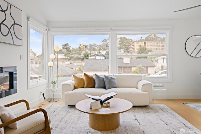 interior space featuring a glass covered fireplace, baseboards, and wood finished floors