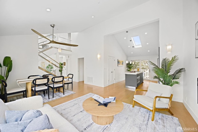 living room featuring light wood finished floors, recessed lighting, visible vents, high vaulted ceiling, and stairs