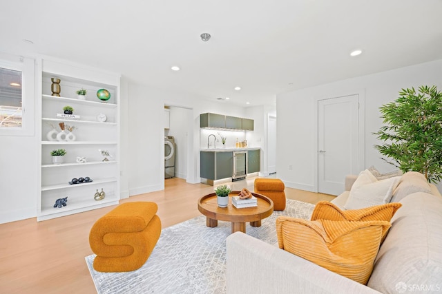 living area with light wood finished floors, recessed lighting, washer / dryer, beverage cooler, and baseboards