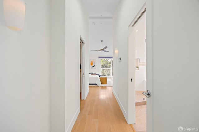 corridor with light wood-style floors and baseboards