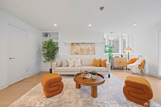 living area with built in shelves, recessed lighting, wood finished floors, visible vents, and baseboards