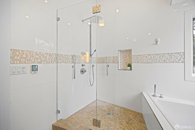 full bathroom with a garden tub, a shower stall, and tile walls