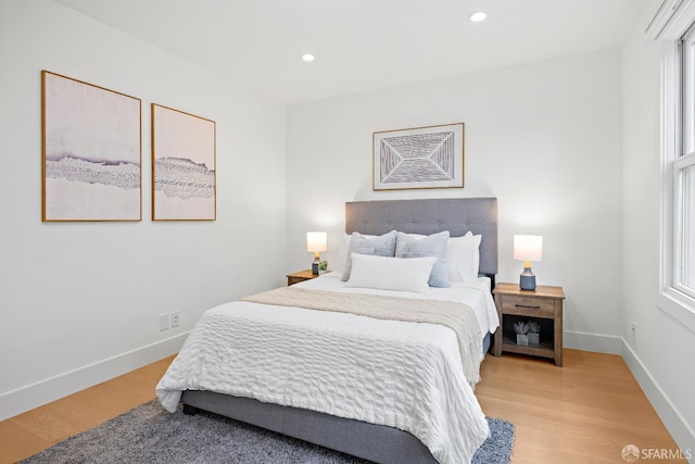 bedroom featuring light wood finished floors, multiple windows, recessed lighting, and baseboards