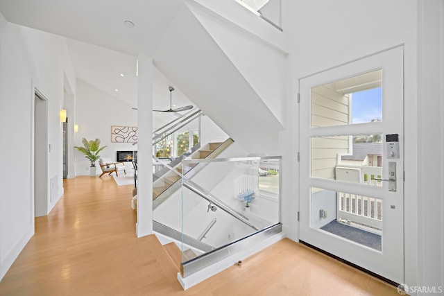 foyer with a ceiling fan, a glass covered fireplace, plenty of natural light, and light wood-style flooring