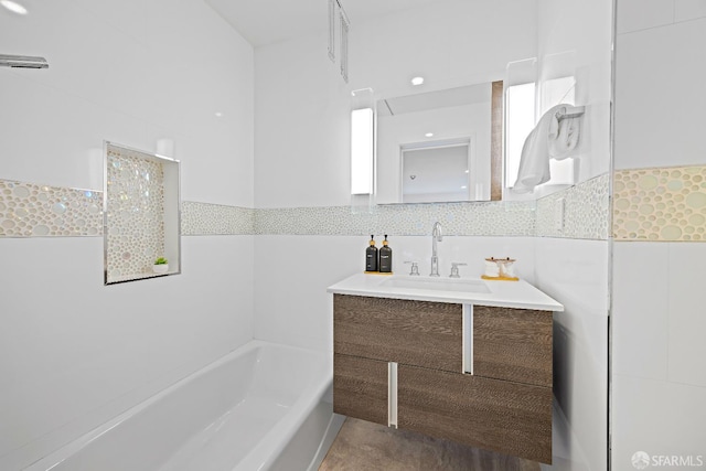 bathroom featuring a tub to relax in, tile walls, and vanity