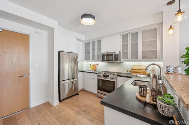 170 King St Unit 1006, San Francisco, CA 94107 - kitchen with stainless steel appliances, light wood-style floors, tasteful backsplash, white cabinets, and dark countertops