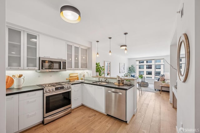 170 King St Unit 1006, San Francisco, CA 94107 - kitchen with stainless steel appliances, dark countertops, a peninsula, white cabinets, and backsplash